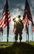 Soldier standing before American flags at sunset